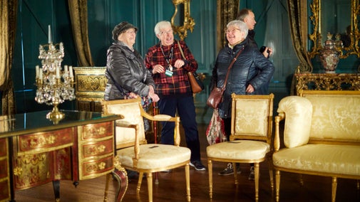 Three women laughing in a blue room with gold furniture